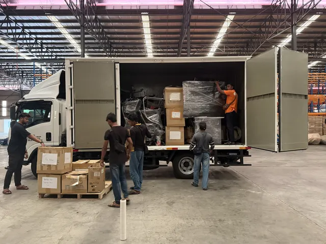 Crew loading boxes and wrapped furniture into the lorry at a warehouse