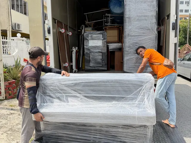 Crew loading a wrapped sofa onto the lorry tailgate