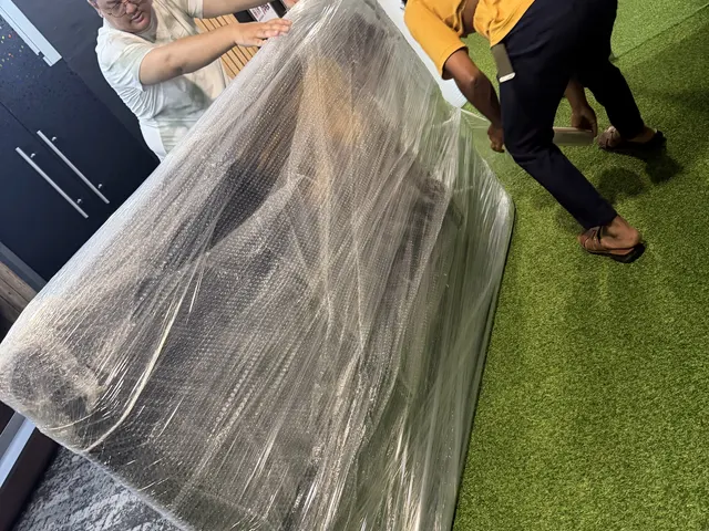 Movers stretch-wrapping a large panel at an office move