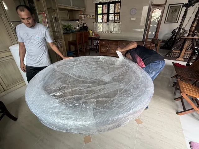 Movers wrapping a round table at a landed house