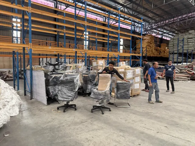 Wrapped office chairs and furniture staged in a warehouse